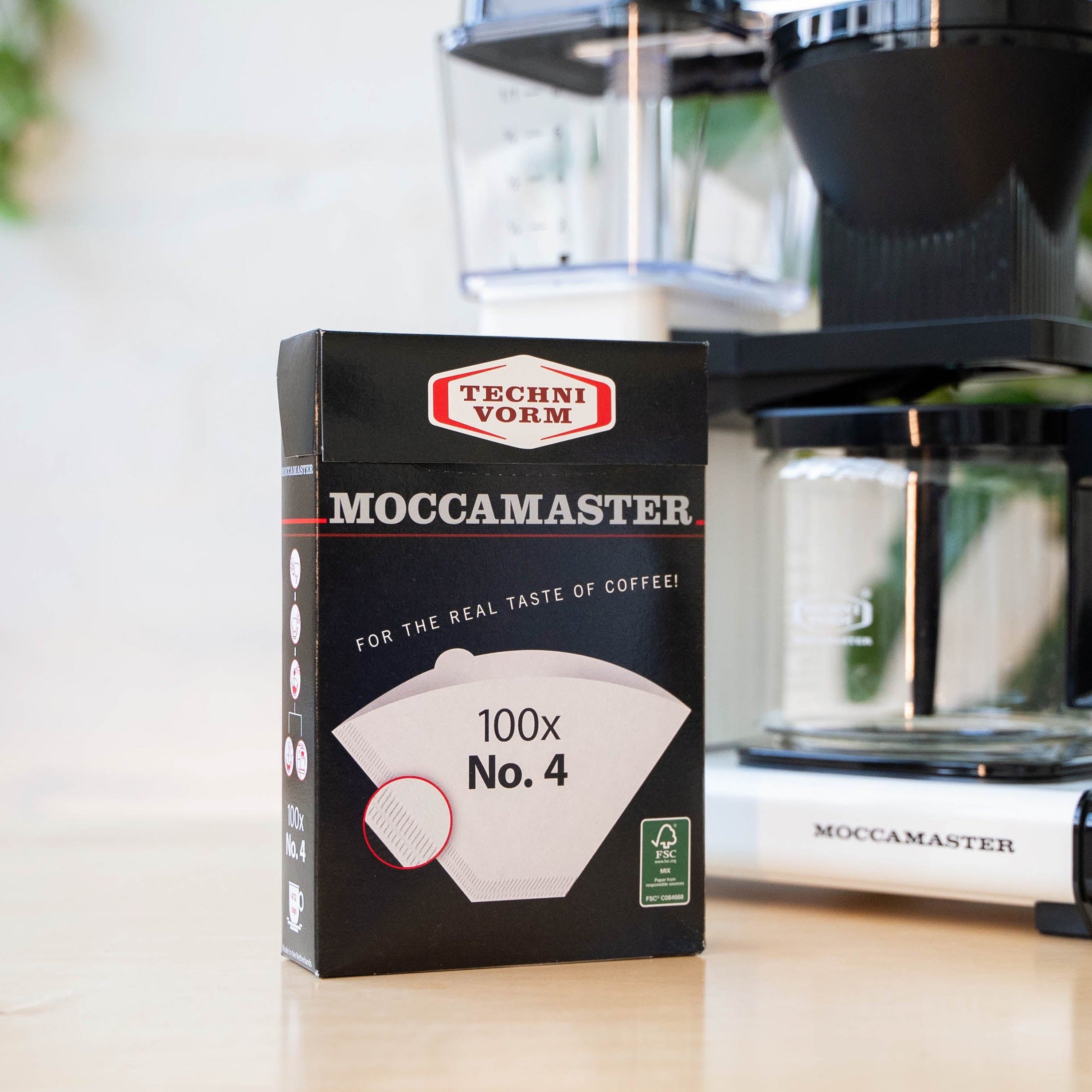 Comandante black coffee grinder with Moccamaster #4 filters, showcasing the grinder's sleek design and filter compatibility.