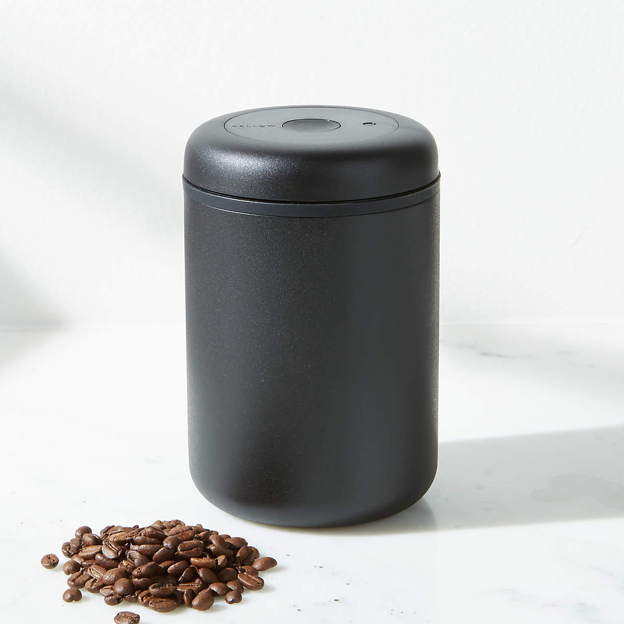 Large Fellow Canister coffee grinder by Comandante with a sleek, modern design and clear lid for storing freshly ground coffee.