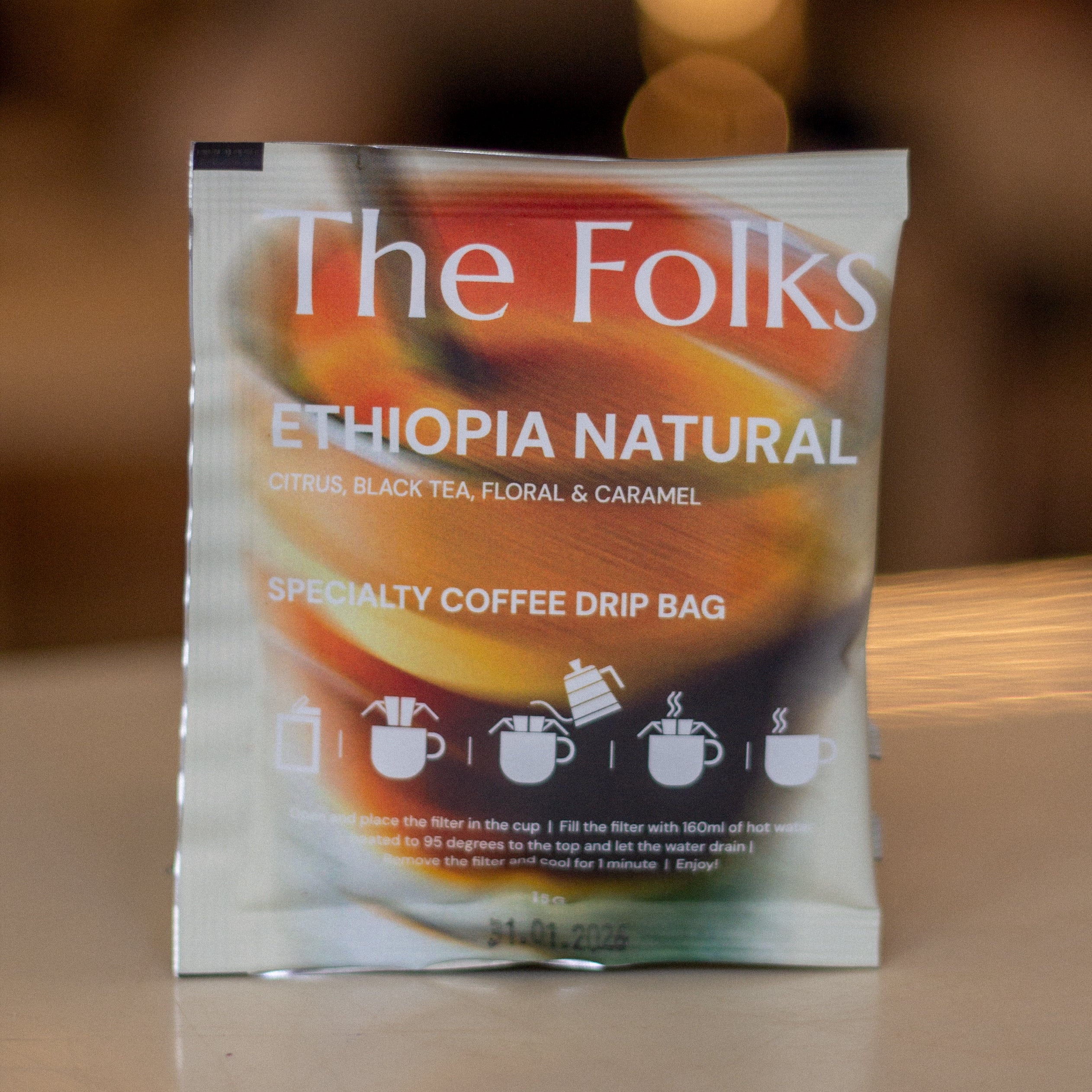 Pack of The Folks Colombia drip coffee beans with Flor de Azafrán label, showcasing fresh coffee beans in a natural setting.