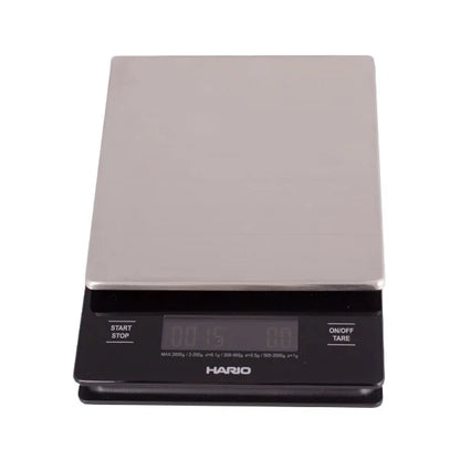 Black Comandante coffee grinder with Hario V60 metal drip scale for precise brewing and grinding coffee beans.