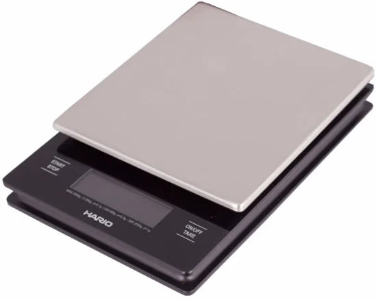 Black Comandante coffee grinder with Hario V60 metal drip scale for precise brewing and grind measurement.