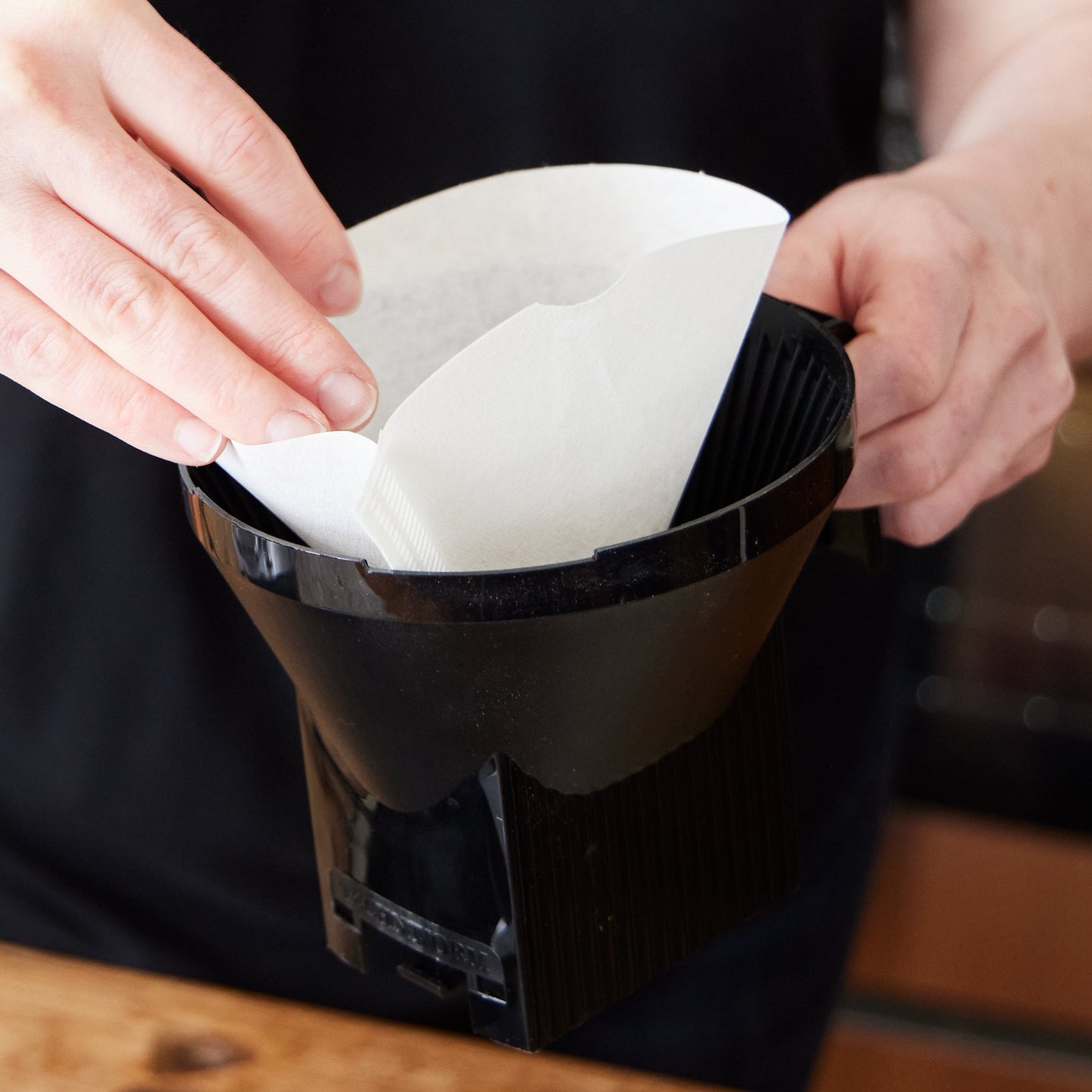 Comandante black coffee grinder with Moccamaster #4 filters for precise brewing, showing the grinder and filters in the image.