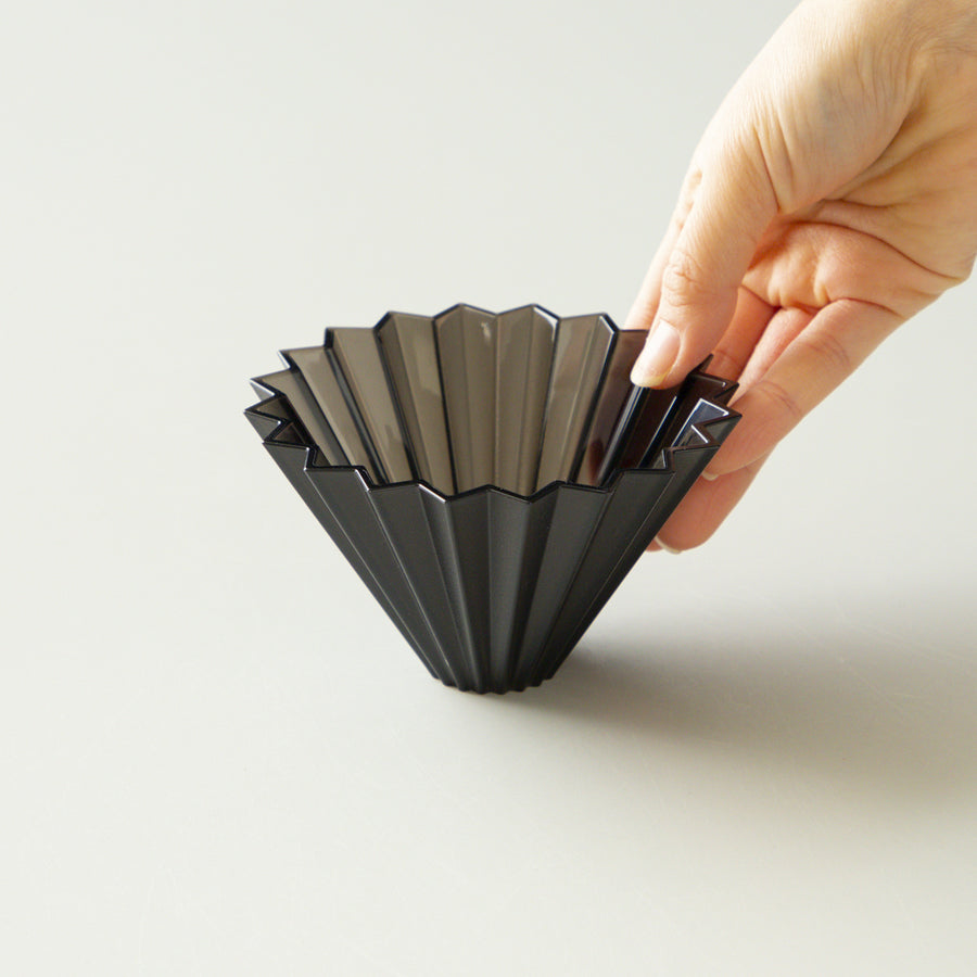 Comandante Origami Air S black plastic coffee grinder with a compact design and manual grinding mechanism.