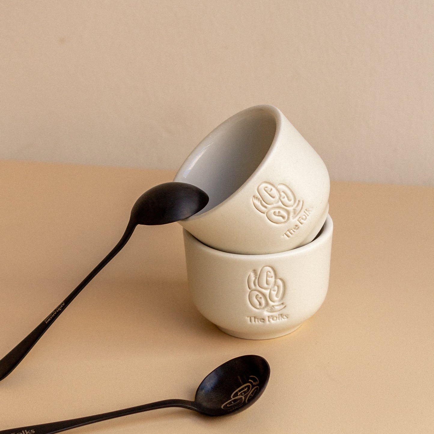 Ceramic mug from The Folks alongside a Comandante coffee grinder, featuring a sleek design and neutral colors.