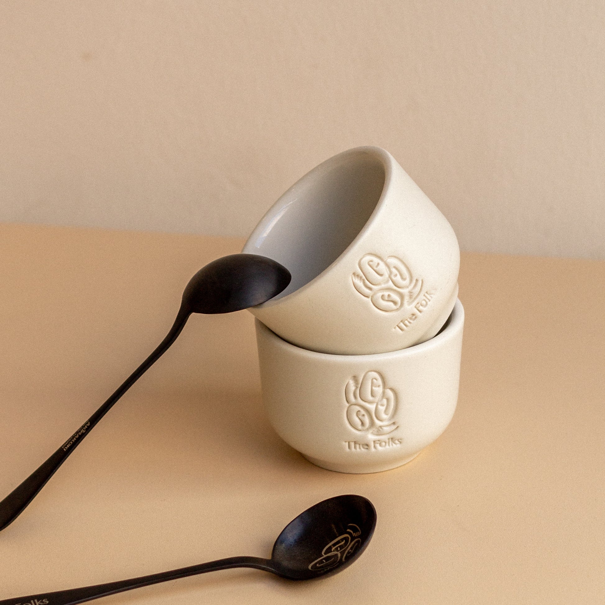 Ceramic mug from The Folks alongside a Comandante coffee grinder, featuring a sleek design and neutral colors.