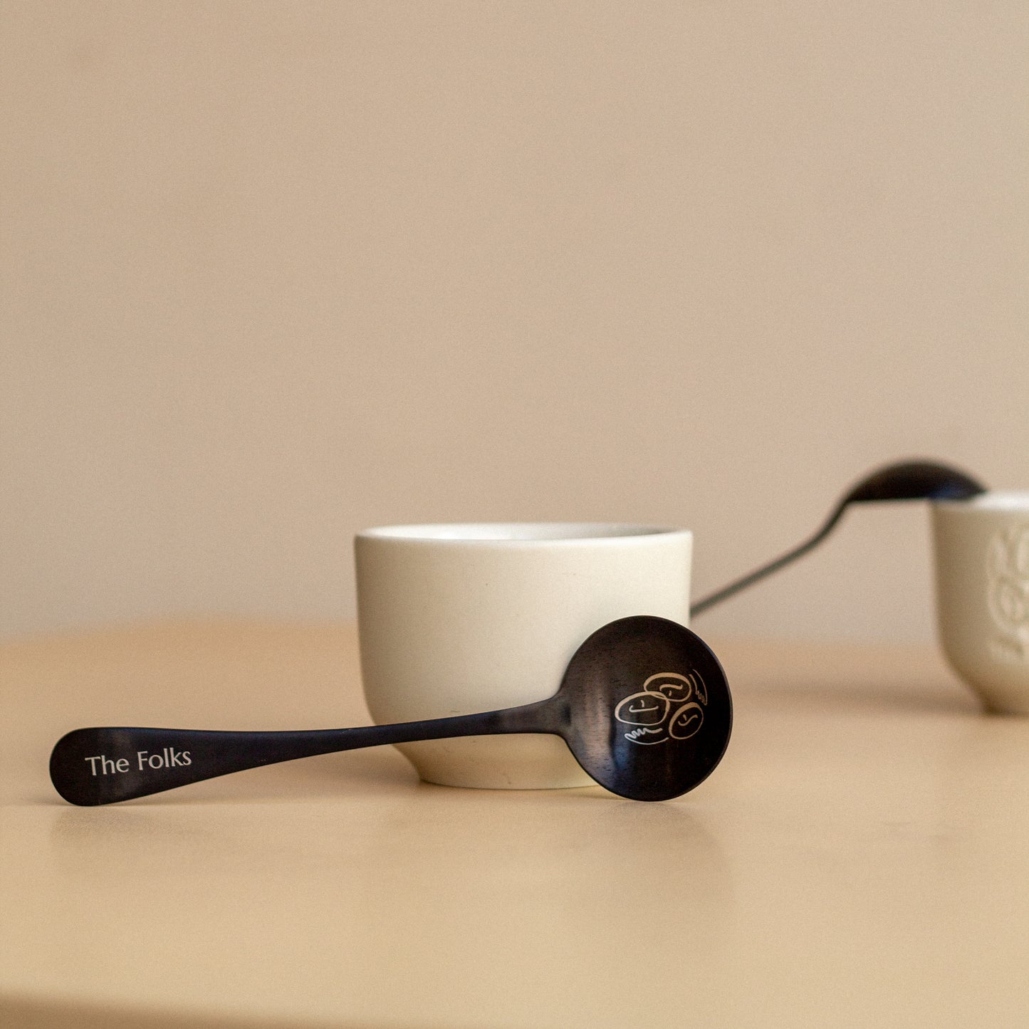 Comandante coffee grinder with a The Folks cupping spoon for tasting and brewing coffee, featuring a sleek design and durable build.