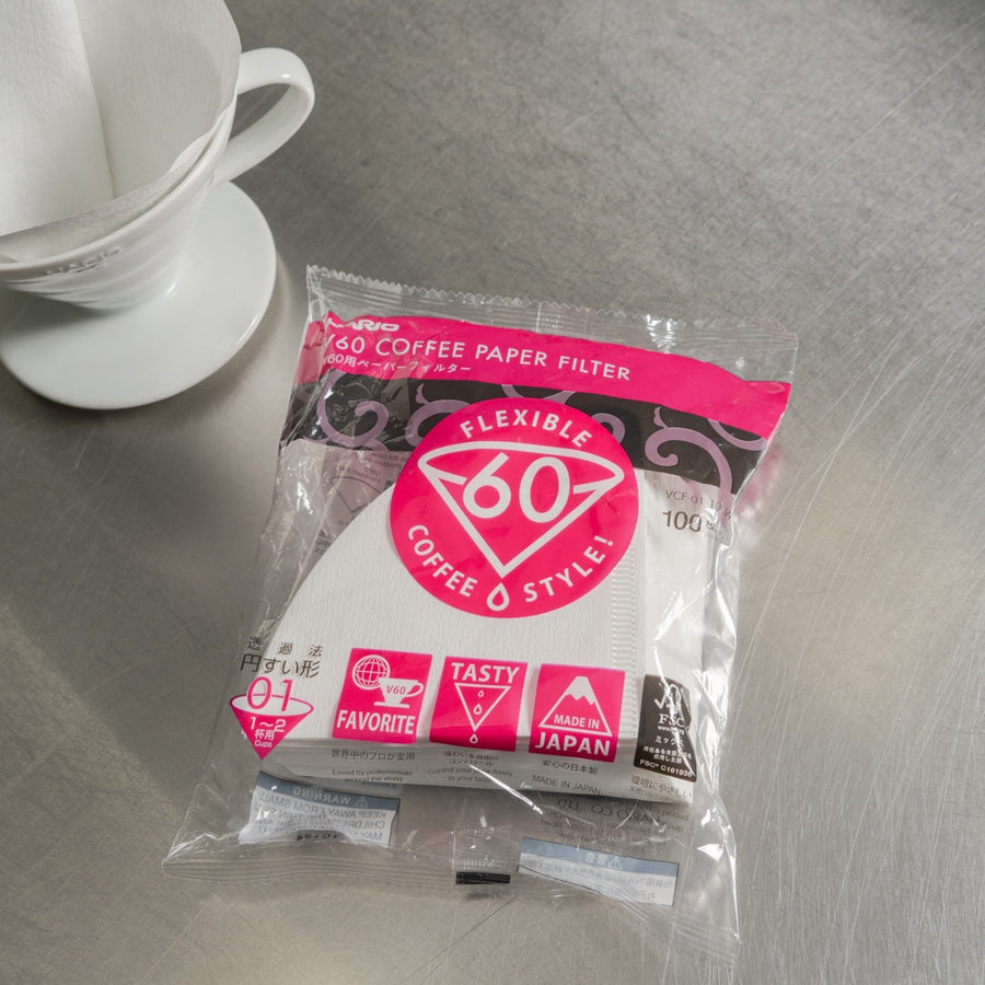 Comandante coffee grinder with Hario V60 Size 01 coffee paper filters for brewing fresh, flavorful coffee.