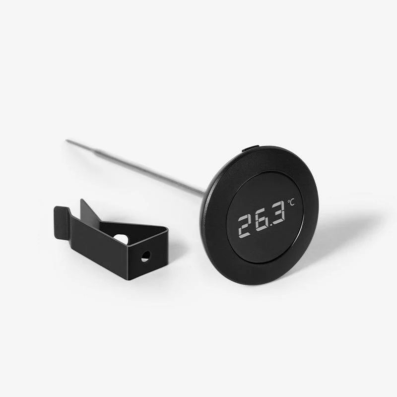 Comandante coffee grinder with Timemore digital thermometer attached, showing a close-up of the grinder's burrs and temperature display.