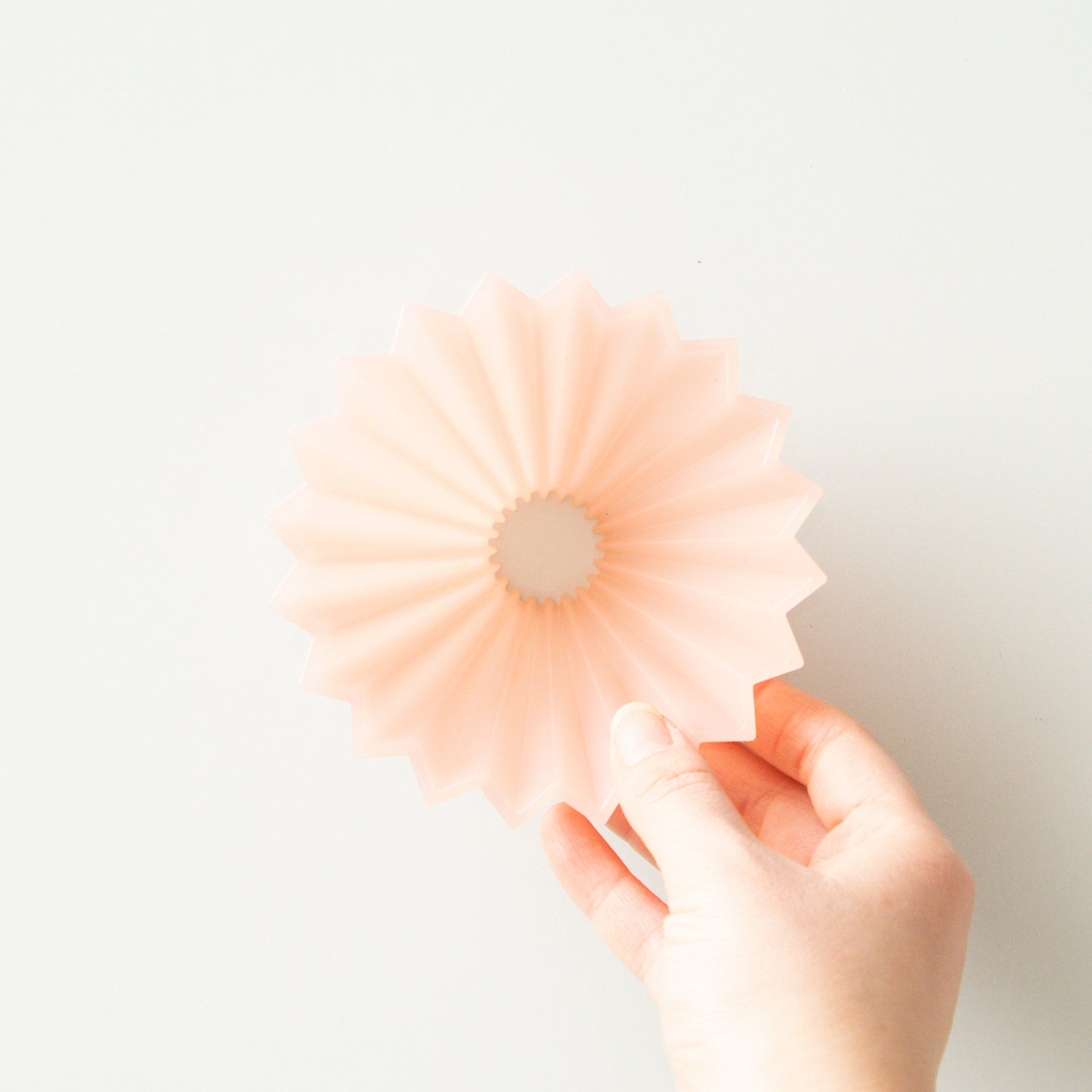 Pink Comandante Origami Air S plastic coffee grinder with a compact design and ergonomic handle for easy grinding.