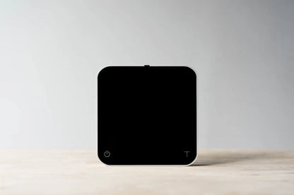 Comandante coffee grinder alongside Acaia Pearl 2021 coffee scale in pitch black, showing high-precision brewing equipment.